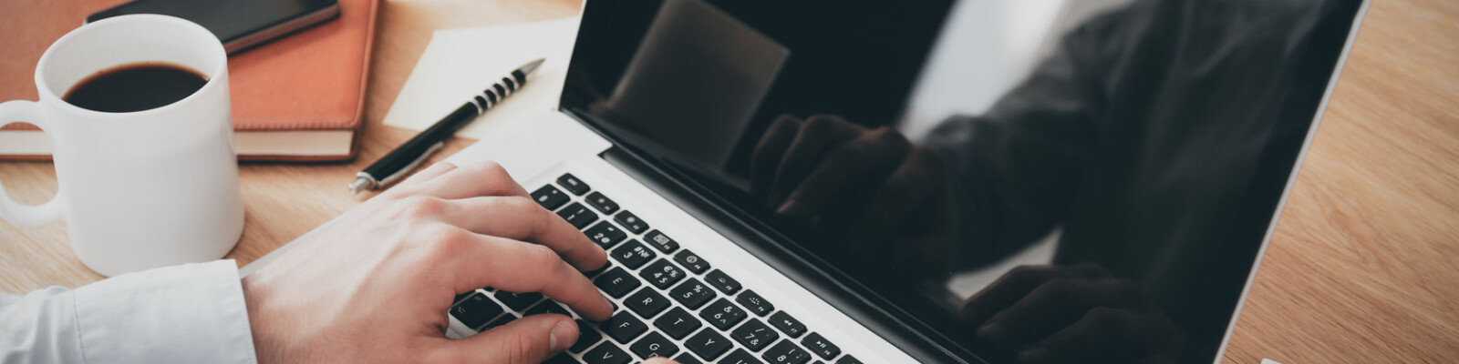 Businessman at work. Close-up top view of man working on laptop while sitting at the wooden desk